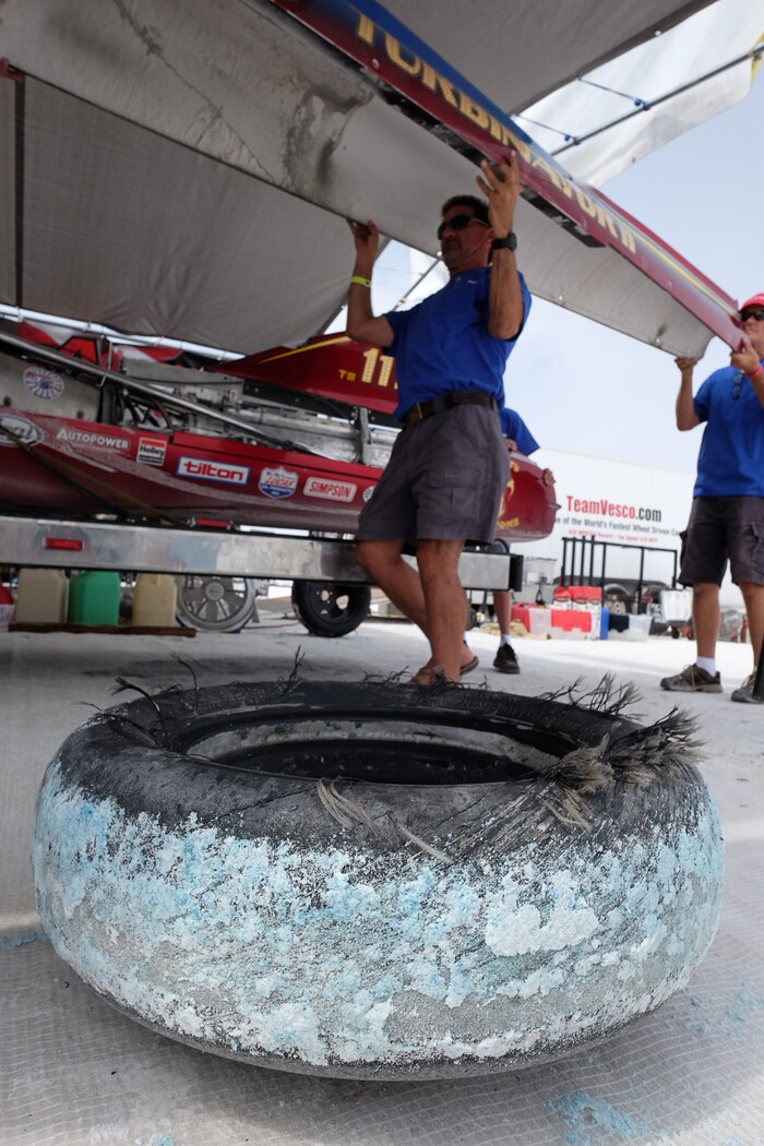 (Francisco Kjolseth  |  The Salt Lake Tribune)  With a shredded tire from an earlier run, crew of the Vesco Turbinator from Rockville, Utah, take the skin off the vehicle following a run during Speed Week at the Bonneville Salt Flats outside Wendover on Monday, Aug. 14, 2017. The Turbinator is the fastest wheel driven vehicle with an international speed record of 458 miles per hour. 