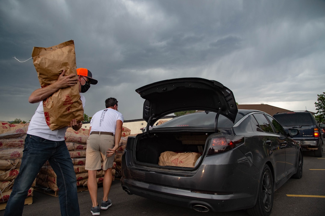 (Francisco Kjolseth  |  The Salt Lake Tribune) Nelson Abbott , left, and Jared Smith load 50-pound bags of potatoes in people’s trunks as the third “Miracle Project” for the nonprofit foundation which raises money to purchase food produced by Utah farmers and then gives to residents in need, takes place at the Utah State Fairpark in Salt Lake City on Monday, July 27, 2020. The food donation from the Utah Farm Bureau’s “Farmers Feeding Utah” program provided food for 600 individuals and families who have recently become unemployed due to the coronavirus.