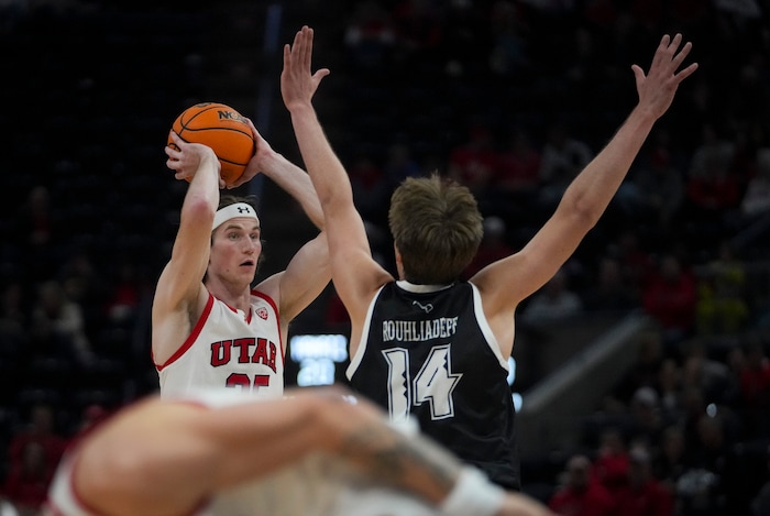 (Bethany Baker  |  The Salt Lake Tribune) Utah Utes center Branden Carlson (35) looks to pass the ball as Hawaii Warriors forward Harry Rouhliadeff (14) blocks at the Delta Center in Salt Lake City on Thursday, Nov. 30, 2023.