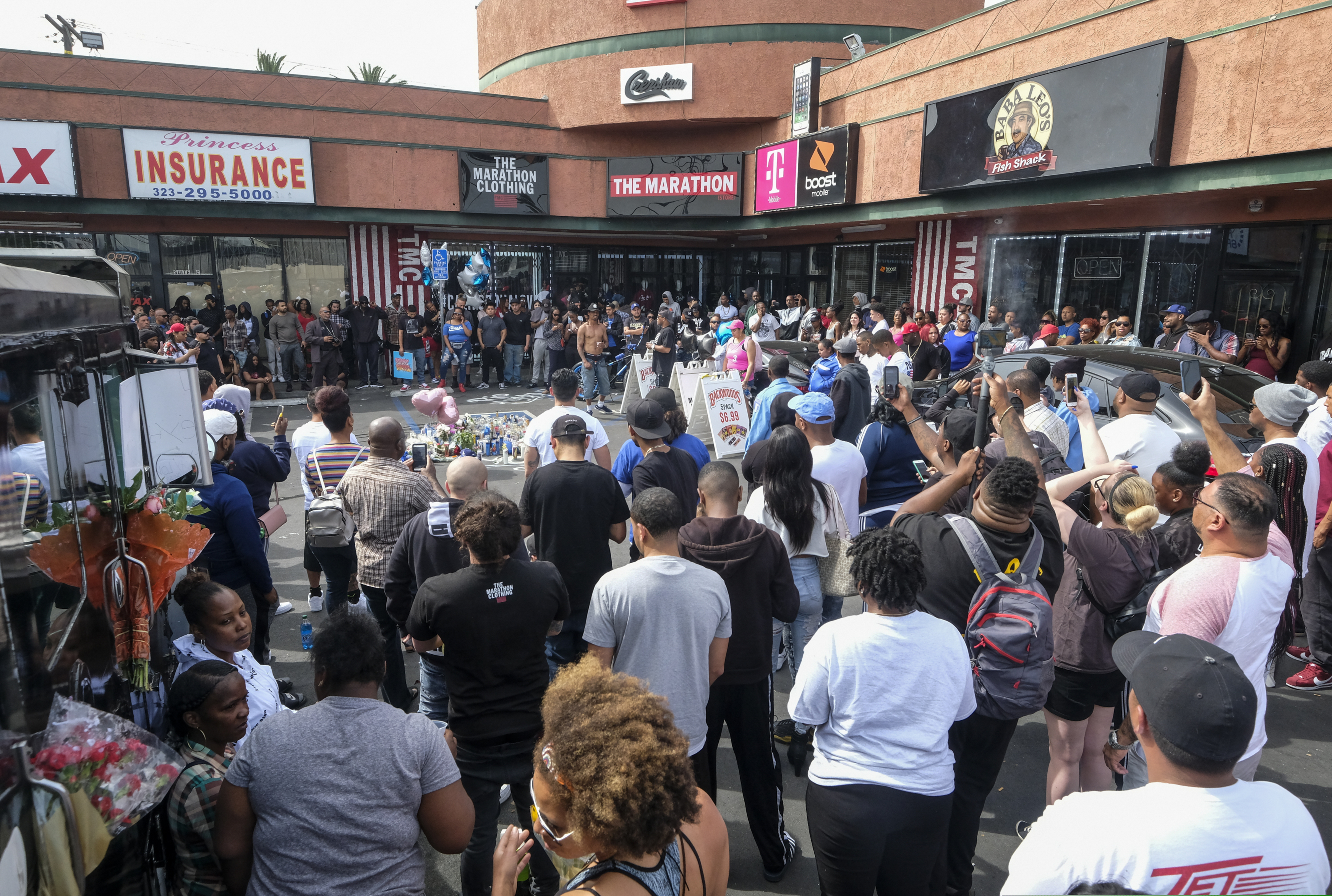 (Ringo H.W. Chiu | The Associated Press) Fans of rapper Nipsey Hussle gather at a makeshift memorial in the parking lot of the Marathon Clothing store in Los Angeles, Monday, April 1, 2019. Hussle was killed in a shooting outside his clothing store on Sunday.