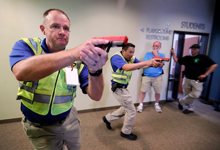 (Tony Gutierrez | AP Photo) In this July 21, 2019 photo, Police officers David Riggall, left, and Nick Guadarrama, center, demonstrate to students Stephen Hatherley, center rear, and Chris Scott, right rear, how to clear a hallway intersection during a security training session at Fellowship of the Parks campus in Haslet, Texas. While recent mass shootings occurred at a retail store in El Paso, Texas, and a downtown entertainment district in Dayton, Ohio, they were still felt in houses of worship, which haven’t been immune to such attacks. And some churches have started protecting themselves with guns.
