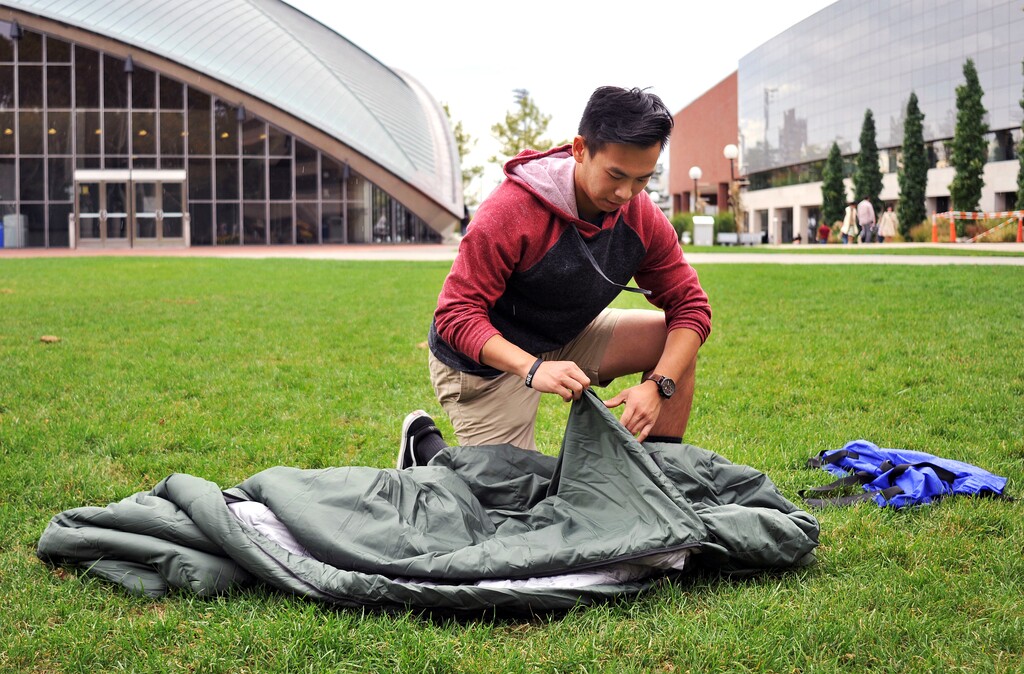 In this Oct. 6, 2017 photo, Vick Liu unrolls his TravlerPack, a lightweight sleeping bag, outside the Kresge Auditorium at the Massachusetts Institute of Technology in Cambridge, Mass . Liu, a finance and political science major, created a line of lightweight sleeping bags for refugees who have few other options to keep warm during winters in the Middle East. Liu and a team of five classmates are sending sleeping bags to resettlement areas in Syria and hope to send more to refugees in Jordan and Lebanon. (AP Photo/Collin Binkley)