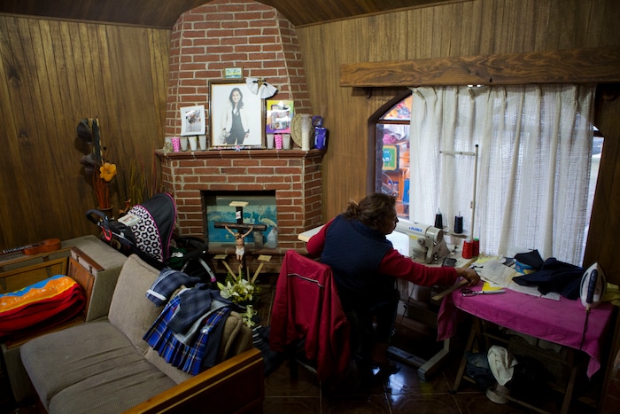 In this Aug. 23, 2017 photo, Juana Pedraza sits next to a small altar in honor of her oldest daughter Jessica, who was murdered at age 29, as she sews school uniforms to order at her home in Villa Cuauhtemoc, Mexico state. Pedraza raised her five daughters to be confident that they are equal to men and that nobody can hold them back. Now tasked with raising her grandson, Jessica's son Leon, she said she's focusing on the other side of the equation: Schools teach kids to read and write, but other values are instilled at home. (AP Photo/Rebecca Blackwell)