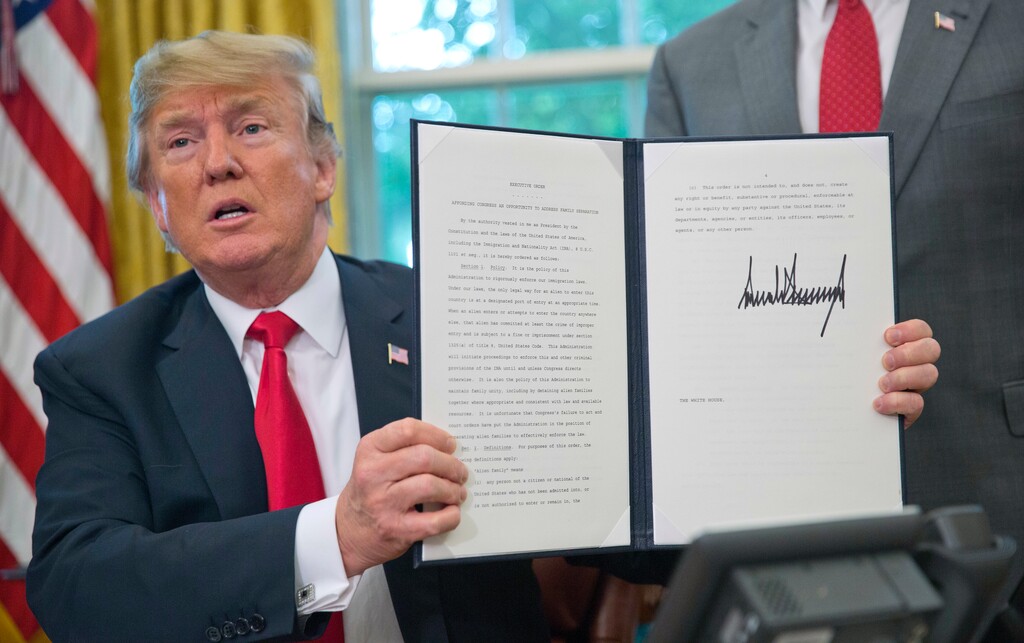 In this June 20, 2018, photo, President Donald Trump holds up the executive order he signed to end family separations at the border, during an event in the Oval Office of the White House in Washington. Trump is distorting the truth when it comes to the impact of his administration’s policy regarding separating children from their parents at the U.S. border. (AP Photo/Pablo Martinez Monsivais)