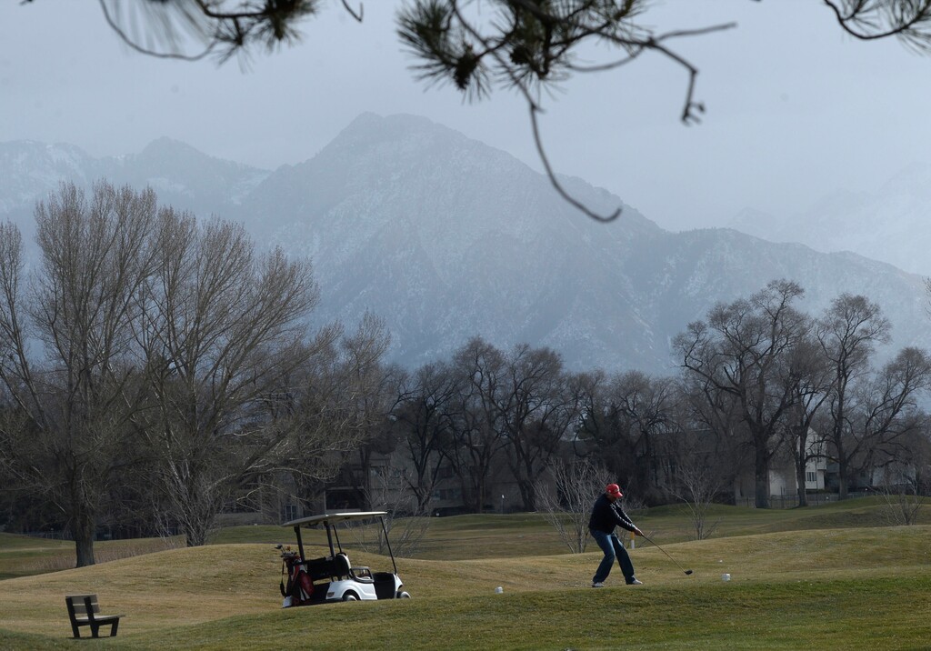 (Al Hartmann  |  The Salt Lake Tribune) Golfer gets one last game in Wednesday Dec. 20 at Forest Dale golf course in Salt Lake City before snow arrives later in the day.   Dust from recent winds hangs in the air obscuring Wasatch Mountains to the east.