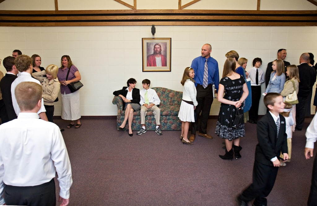 (The Church of Jesus Christ of Latter-day Saints) Members chat in a foyer at church. The new Sunday schedule may reduce such informal conversations.