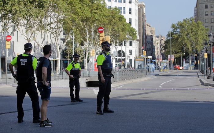 Police officers cordon off a street in Barcelona, Spain, Thursday, Aug. 17, 2017. Police in the northern Spanish city of Barcelona say a white van has jumped the sidewalk in the city's historic Las Ramblas district, injuring several people. (AP Photo/Manu Fernandez)