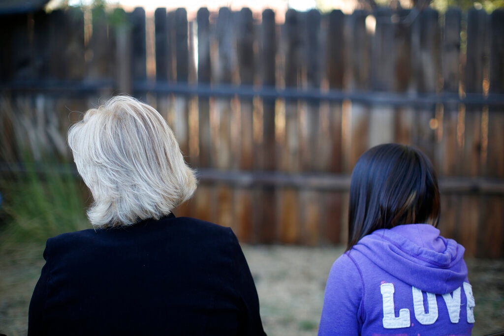 (Dario Lopez-Mills | AP) MJ and her adoptive mother sit for an interview with The Associated Press in Sierra Vista, Ariz., Oct. 27, 2021. State authorities placed MJ in foster care after learning that her father, the late Paul Adams, sexually assaulted her and posted video of the assaults on the Internet.