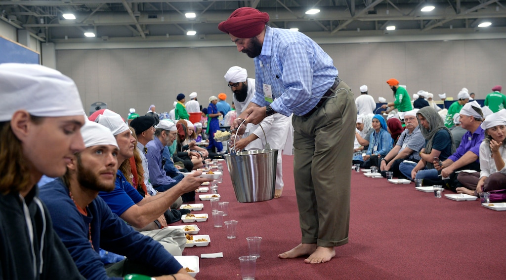 (Al Hartmann  |  The Salt Lake Tribune) Several thousand attending the Parliament of the World's Religions wearing head covering sit together as equals on the floor of the Salt Palace Convention Center on Oct. 16, 2019. Attendees were served food by members of the Sikh religious community at a traditional Langar, a 500-year-old Sikh religion tradition where vegetarian food is served to all for free, regardless of religion or class.