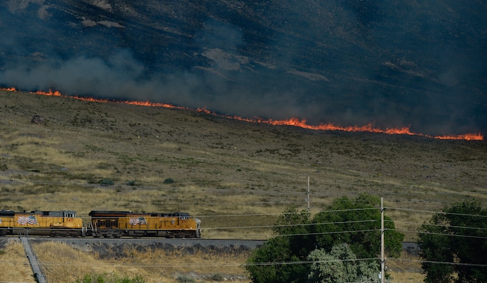 (Francisco Kjolseth  |  The Salt Lake Tribune)  A Union Pacific train passes the fire line as crews battle a grass fire in Tooele county being dubbed the the Green Ravine fire at it burns on Tuesday, Sept. 3, 2019.