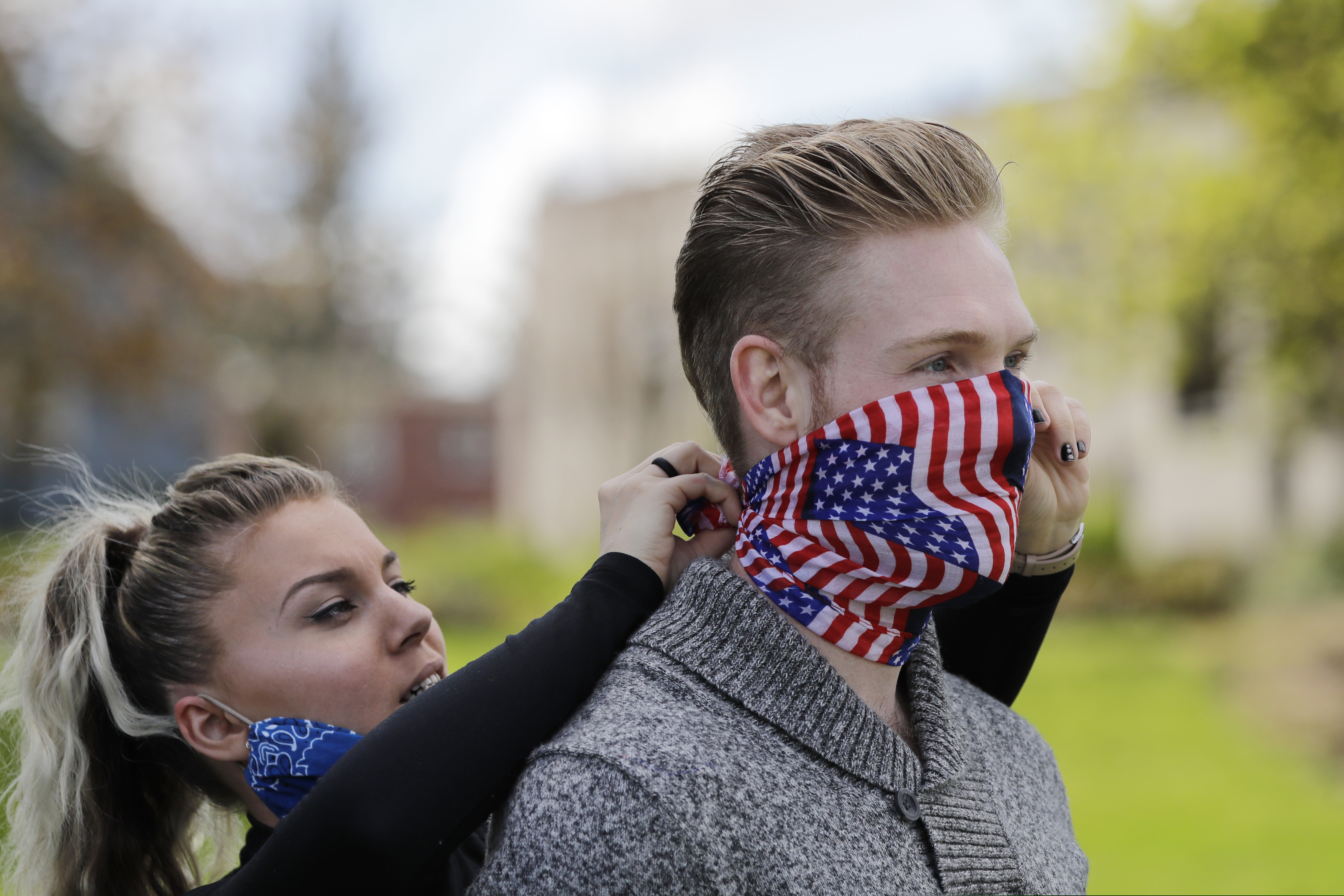 (Elaine Thompson | AP) Bobby Mcgaughy, left, ties a mask on her husband Kynan before a protest opposing Washington state's stay-home order to slow the coronavirus outbreak Sunday, April 19, 2020, in Olympia, Wash. Washington Gov. Jay Inslee has blasted President Donald Trump's calls to "liberate" parts of the country from stay-at-home and other orders that are designed to combat the spread of the coronavirus. Inslee says that Trump is fomenting a potentially deadly "insubordination" among his followers before the pandemic is contained.
