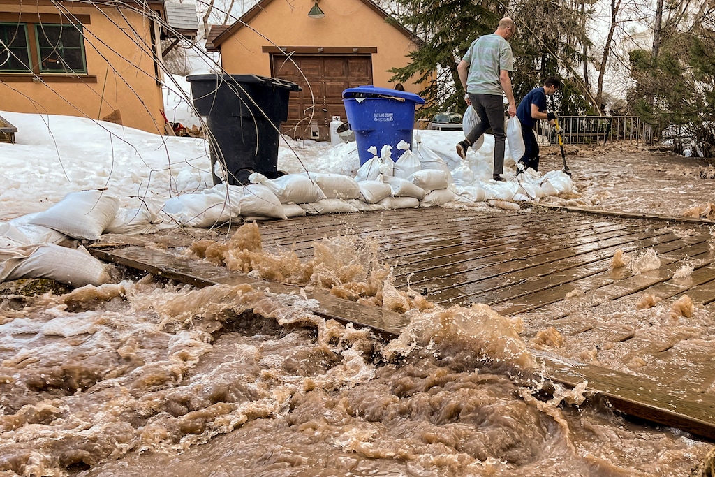 (Trent Nelson | The Salt Lake Tribune) People work to save a home as Emigration Creek rises in Emigration Canyon on Wednesday, April 12, 2023. As public officials have urged Utahns to prepare for flooding by purchasing insurance policies, thousands may not have access to it and few communities participate in a federal program to make it more affordable.