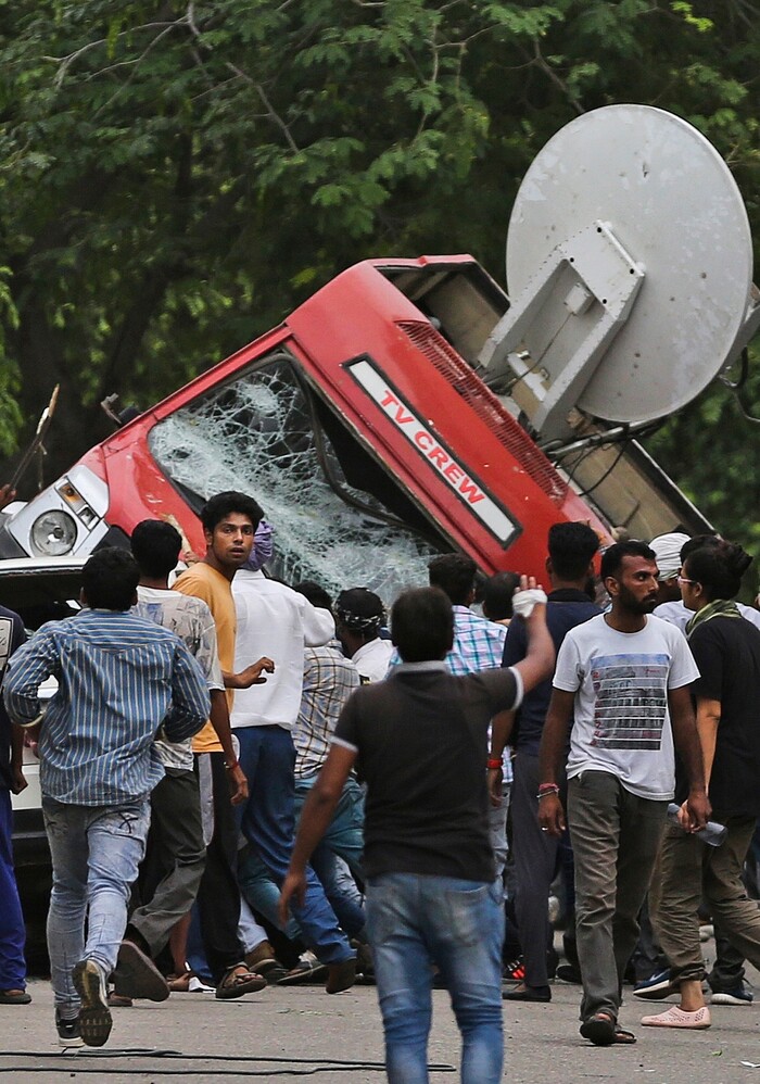 Dera Sacha Sauda sect members overturn an OB van on the streets of Panchkula, India, Friday, Aug. 25, 2017. Deadly riots have broken out in a north Indian town after a court convicted their guru, who calls himself Saint Dr. Gurmeet Ram Rahim Singh Ji Insaan, of raping two of his followers. Mobs also attacked journalists and set fire to government buildings and railway stations. (AP Photo/Altaf Qadri)