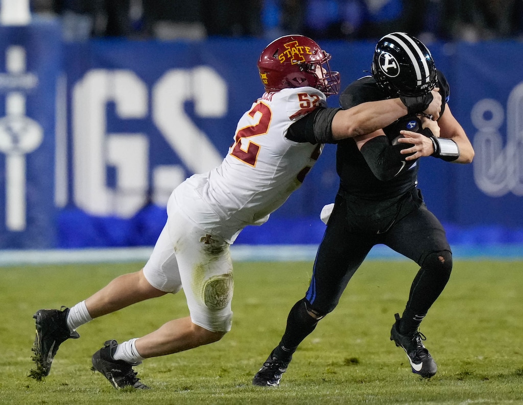 (Francisco Kjolseth | The Salt Lake Tribune) Brigham Young Cougars quarterback Jake Retzlaff (12) has his face mask grabbed by Iowa State Cyclones defensive end Joey Petersen (52) during an NCAA college football game on Saturday, Nov. 11, 2023, in Provo, Utah.