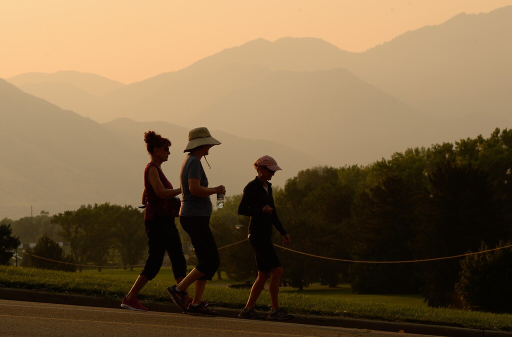 (Francisco Kjolseth  |  The Salt Lake Tribune)  Early morning walkers at Sugarhouse Park in Salt Lake City are silhouetted against a smoke filled landscape as wildfires add to to the poor air quality on Tuesday, Sept. 5, 2017. 