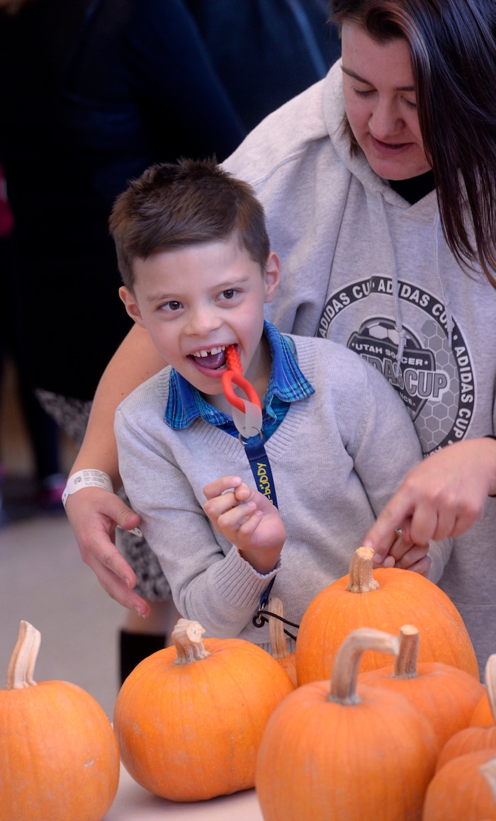 (Al Hartmann | The Salt Lake Tribune)
Sebastian Delgado choses a pumpkin with help from teacher Brittany Hathaway at Kauri Sue Hamilton School in Riverton. Pumpkin were grown by inmates in the Green Thumb Nursery program at Utah State Prison. Thousands of pumpkins were harvested this season for donation to local children with significant disabilities.
