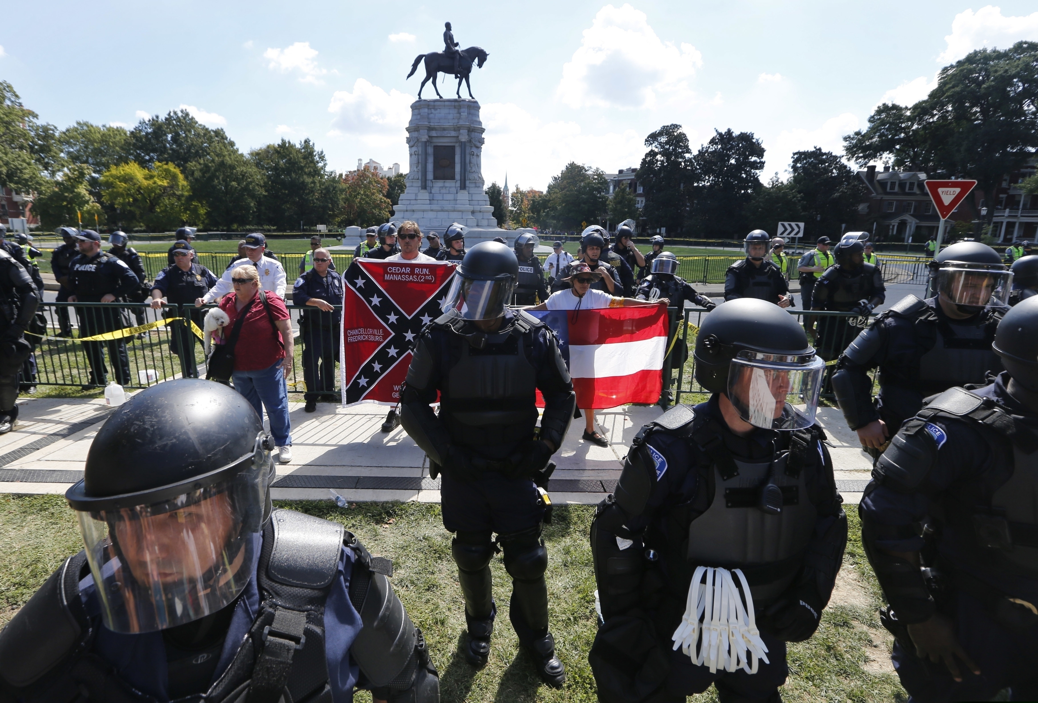 FILE - In this Sept. 16, 2017 file photo, State Police keep a small group of Confederate protesters separated from counter demonstrators in front of the statue of Confederate General Robert E. Lee on Monument Avenue in Richmond, Va. The Confederate statue in Charlottesville, that became a rallying point for white nationalists, was found vandalized Wednesday, July 24, 2019, with an expletive against President Donald Trump. (AP Photo/Steve Helber, File)