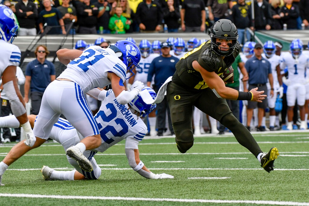 Oregon quarterback Bo Nix makes a cut past BYU defensive back Ammon Hannemann (22) and linebacker Max Tooley (31) during the first half of an NCAA college football game, Saturday, Sept. 17, 2022, in Eugene, Ore. (AP Photo/Andy Nelson)