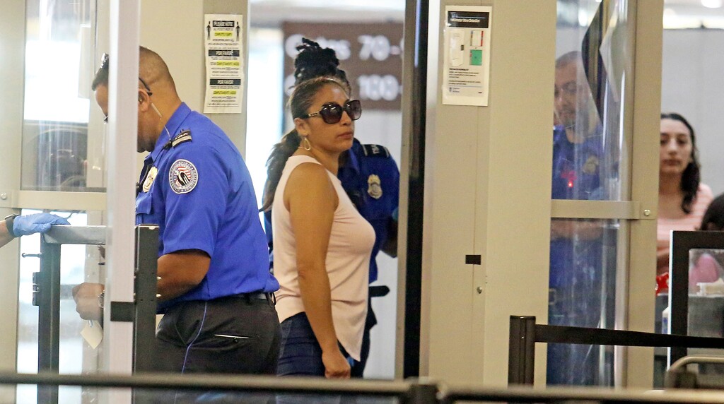 (Red Huber/Orlando Sentinel via AP) Alejandra Juarez,38, center, passes through TSA screening at the Orlando International Airport on Friday, Aug. 3, 2018 in Orlando, Fla.  Juarez, the wife of a former Marine is preparing to self-deport to Mexico in a move that would split up their family.  Juarez had raised two American citizen daughters, ages 16 and 8, with her husband Temo Juarez, a naturalized citizen and now is headed back to Mexico where she no longer had any family or friends.