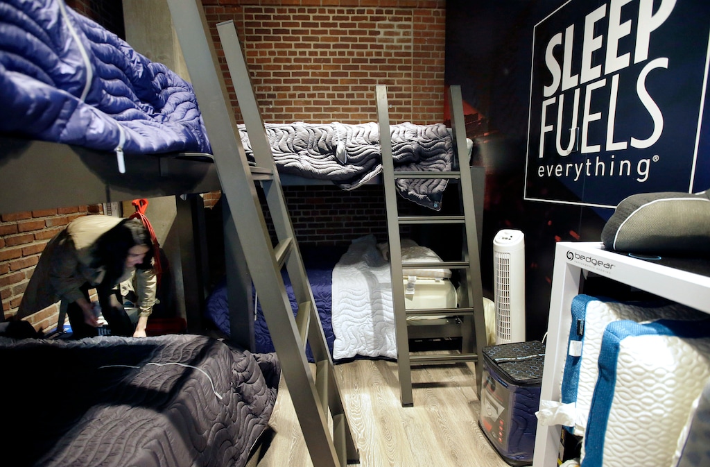 In this Wednesday, May 31, 2017, photo, Zineb Curran, left, Boston Red Sox senior director of corporate communications, arranges bedding in a nap station near the team's clubhouse at Fenway Park in Boston. Day-night doubleheaders. Cross-country travel. Rain delays and extra innings. A baseball season can play havoc with a player's sleep schedule, but the Red Sox think they have one answer with a room for napping. (AP Photo/Steven Senne)
