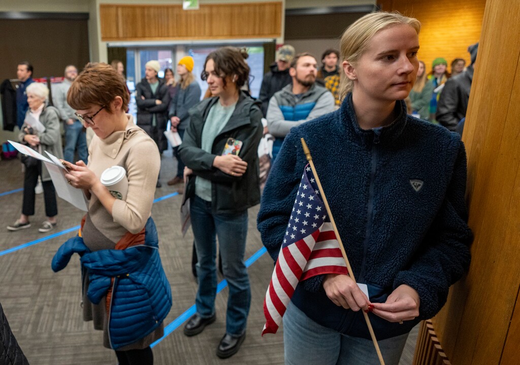 (Rick Egan | The Salt Lake Tribune) Cassidy Bogard holds the American flag, signaling that she is at the end of the line, as voters wait to cast their ballots at the Hogle Zoo, on Tuesday, Nov. 5, 2024.