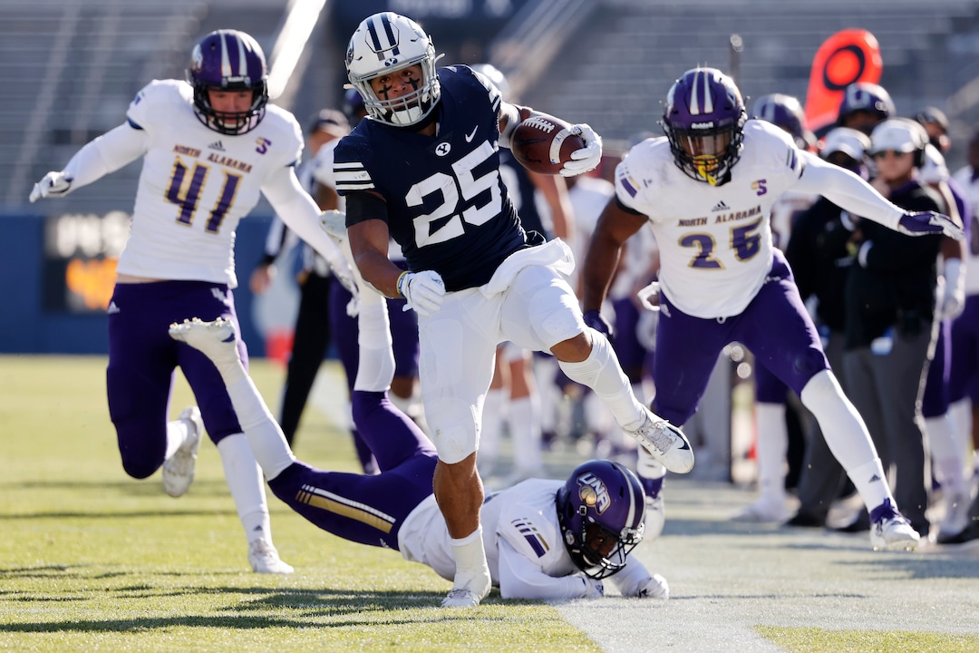 BYU running back Tyler Allgeier (25) runs the ball for a first down past North Alabama cornerback Will Singleton, bottom, defensive end Tyler Antkowiak (41) and linebacker Christon Taylor (25) in the second quarter during an NCAA college football game Saturday, Nov. 21, 2020, in Provo, Utah. (AP Photo/Jeff Swinger, Pool)