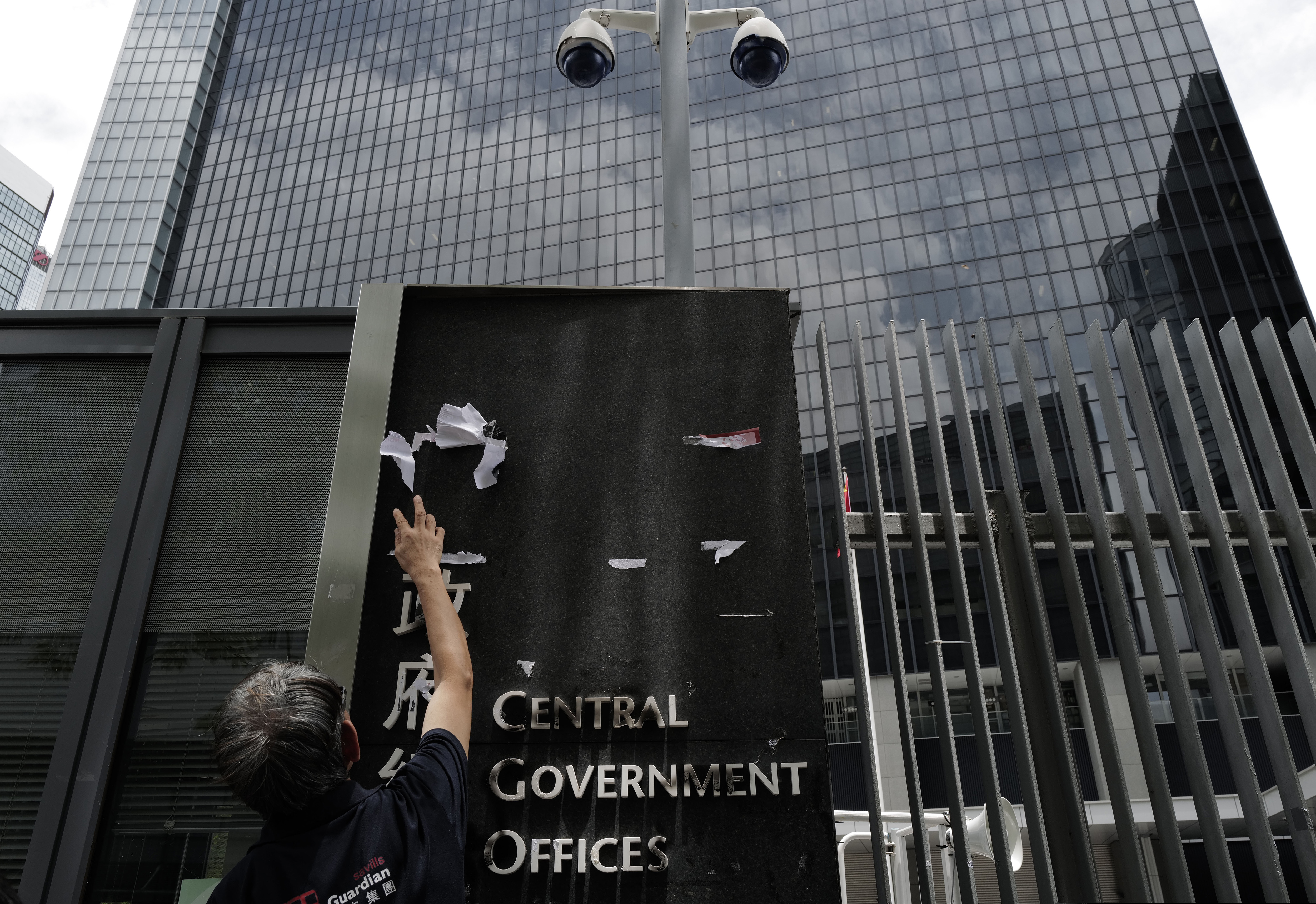 (Vincent Yu | AP Photo) A worker cleans up the main enterance outside government headquarters in Hong Kong, Tuesday, July 2, 2019. Protesters in Hong Kong took over the legislature's main building Monday night, tearing down portraits of legislative leaders and spray painting pro-democracy slogans on the walls of the main chamber.