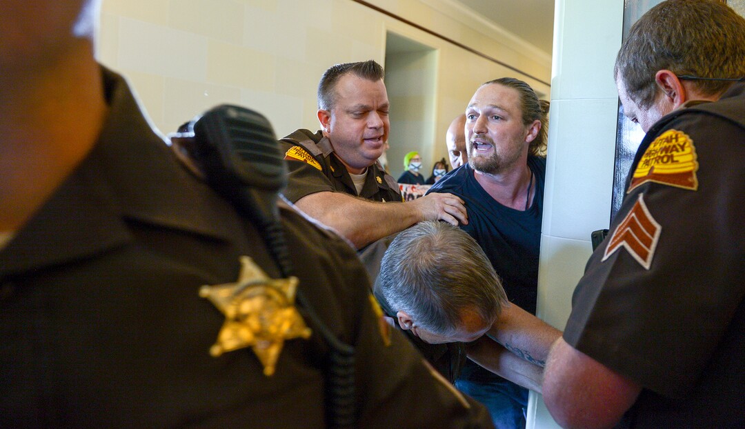 (Leah Hogsten  |  The Salt Lake Tribune) Ethan Petersen with Civil Riot, a SLC-based civil resistance collective, and other opponents of the proposed inland port are escorted out of the Utah Inland Port Authority Board meeting by Utah Highway Patrol officers at the Capitol, June 5, 2019. The Inland Port Authority Board had to cancel its meeting last month after a group of protesters took over the meeting.