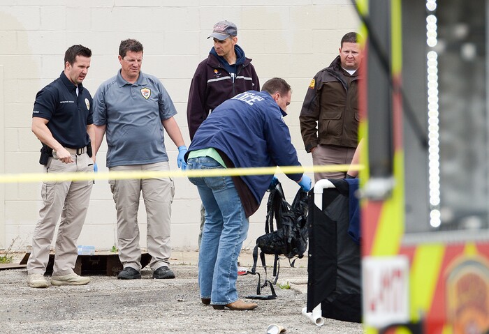 (Leah Hogsten  |  The Salt Lake Tribune)  A West Valley City police detective inspects a backpack found with a body that was recovered from a storm culvert on the grounds of the the vacant Kmart building at 4100 South and 1770 West in West Valley City, Friday, April 6, 2018. 