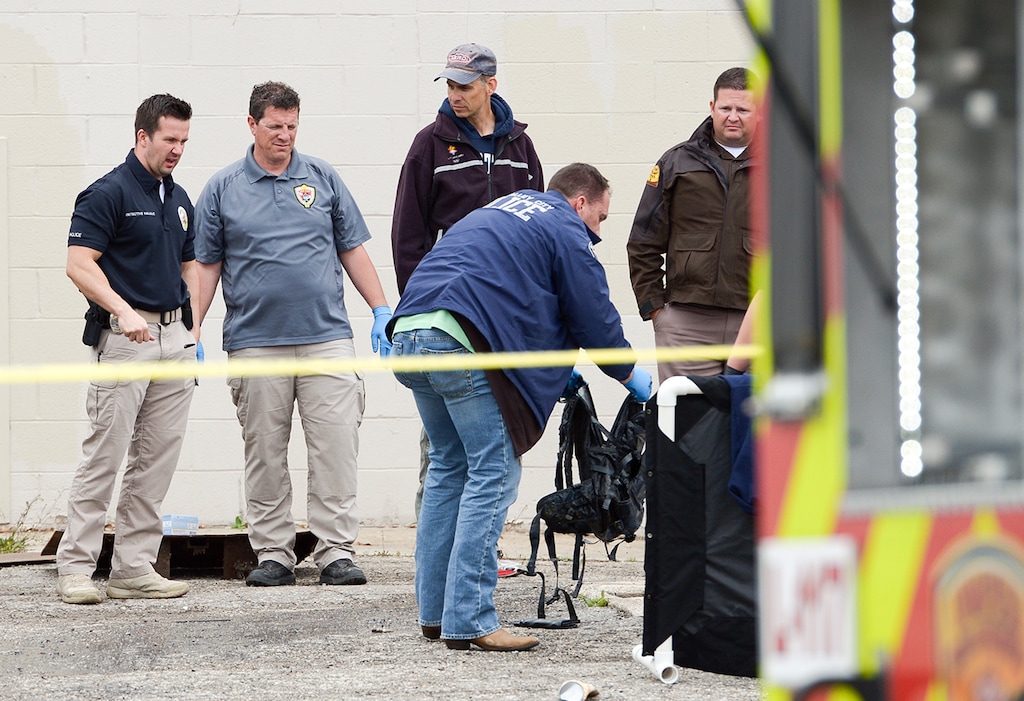 (Leah Hogsten | The Salt Lake Tribune) A West Valley City police detective inspects a backpack found with a body that was recovered from a storm culvert on the grounds of the the vacant Kmart building at 4100 South and 1770 West in West Valley City, Friday, April 6, 2018.