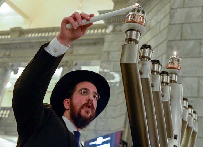 Leah Hogsten  |  The Salt Lake Tribune  Rabbi Avremi Zippel with Chabad Lubavitch of Utah relights the first candle of the menorah during the 12th annual Hanukkah celebration at the Utah Capitol, Dec. 2, 2018. This year's event was also dedicated as 'A Salute to a Hero', in tribute to the late Maj. Brent Taylor of North Ogden, as the menorah was kindled by his wife, Jennie Taylor.