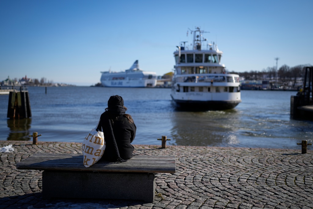 A woman sits on a embarkment in Helsinki, Finland, Monday, April 3, 2023. (AP Photo/Sergei Grits)