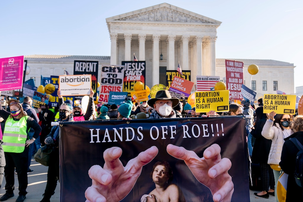 (Andrew Harnik | AP) Stephen Parlato of Boulder, Colo., holds a sign that reads "Hands Off Roe!!!" as abortion rights advocates and anti-abortion protesters demonstrate in front of the U.S. Supreme Court, Wednesday, Dec. 1, 2021, in Washington, as the court hears arguments in a case from Mississippi, where a 2018 law would ban abortions after 15 weeks of pregnancy, well before viability.