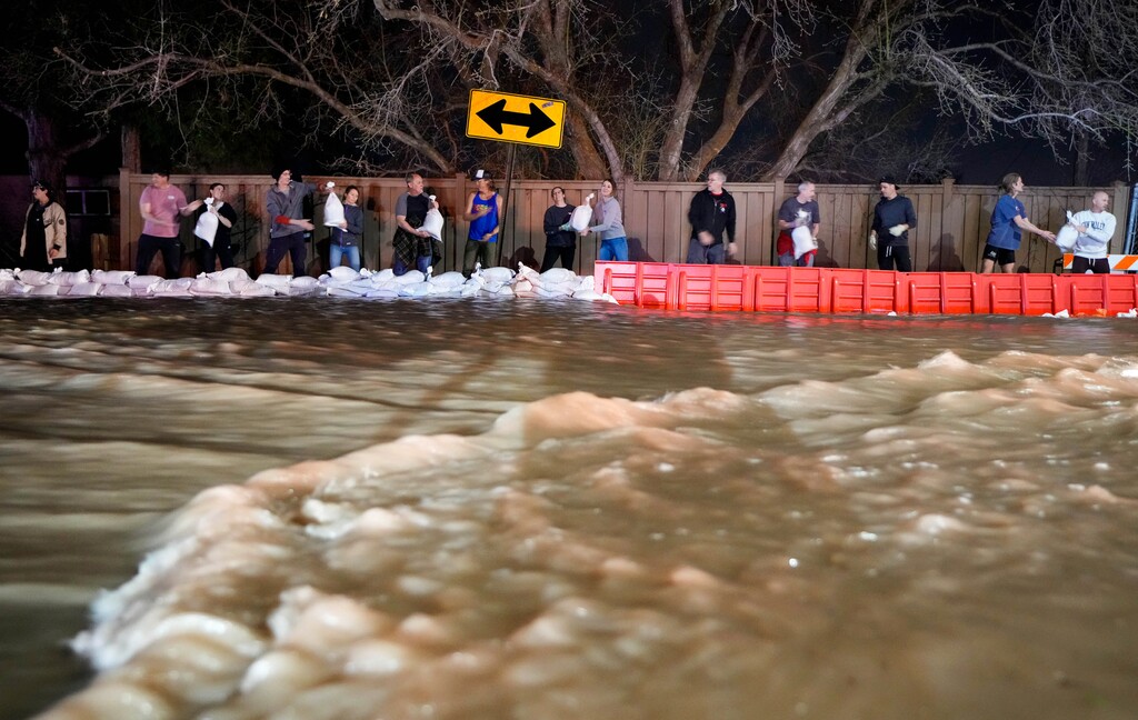 (Francisco Kjolseth | The Salt Lake Tribune) People work to protect homes into the night along 1700 South in Salt Lake City from the rising flow of Emigration Creek through Wasatch Hollow Park on Wednesday, April 12, 2023. 