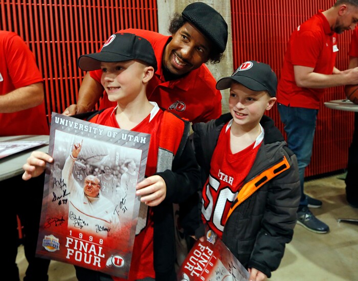 Andre Miller, center, a former Utah player poses for photos with young fans before an NCAA college basketball game between California and Utah on Saturday, Feb. 10, 2018, in Salt Lake City. Players from the 1998 NCAA championship game Utah team were on hand for a halftime ceremony. (AP Photo/Rick Bowmer)