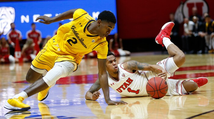Utah guard Justin Bibbins (1) dives for a loose ball as California guard Juhwan Harris-Dyson (2) defends during the second half of an NCAA college basketball game Saturday, Feb. 10, 2018, in Salt Lake City. (AP Photo/Rick Bowmer)