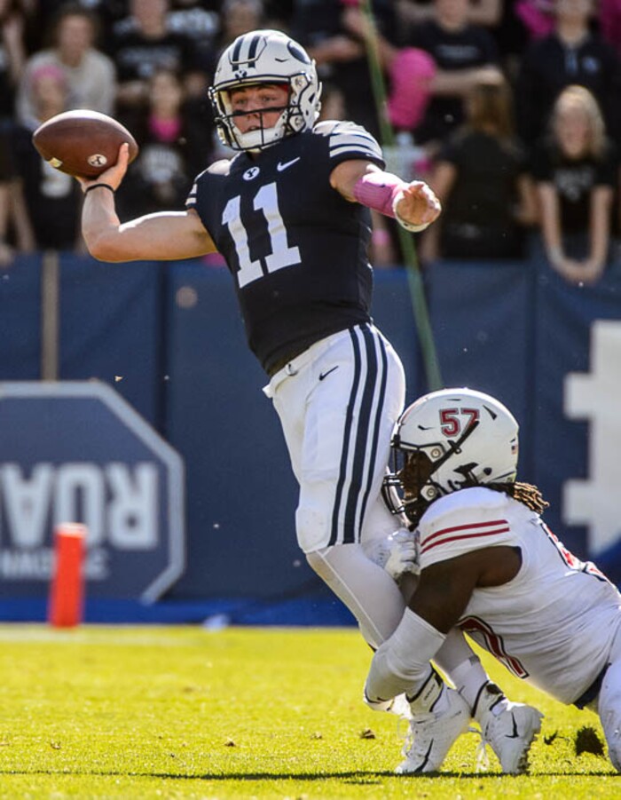 (Trent Nelson | The Salt Lake Tribune)  
Brigham Young Cougars quarterback Zach Wilson (11) throws the ball away as he's brought down by Northern Illinois Huskies linebacker Kyle Pugh (57) as BYU hosts Northern Illinois, NCAA football in Provo, Saturday Oct. 27, 2018.