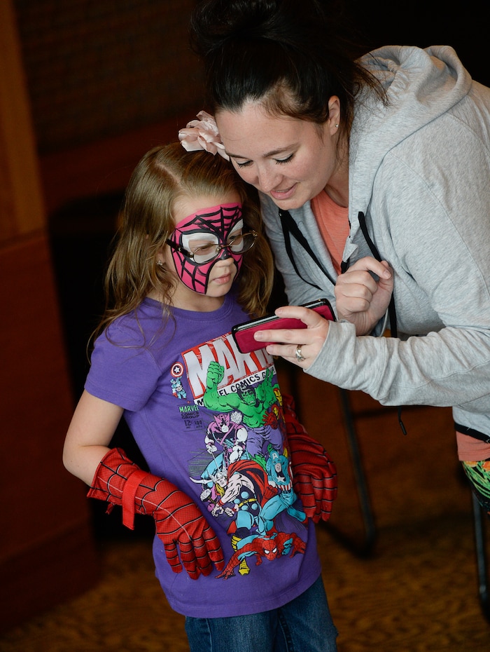 (Francisco Kjolseth  |  The Salt Lake Tribune)  Jamie Harrison shows her daughter Ashlynn, 6, her photos as Utah-based military families gather for the Salt Lake opening night of the all-new Marvel Universe LIVE! Age of Heroes, witnessing their favorite Marvel super heroes, including The Avengers, Spider-Man and the Guardians of the Galaxy in an action-packed adventure at the Maverik Center on Thursday, Sept. 28, 2017. MarvelÕs greatest military Super Hero Captain America was partnered with Got Your 6, a military veteran non-profit group dedicated to empowering veterans to lead and build stronger communities across America.
