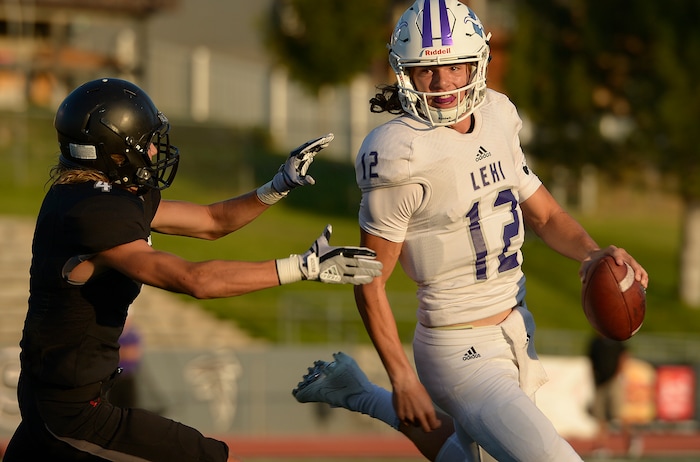(Leah Hogsten  |  The Salt Lake Tribune) Lehi's quarterback Cammon Cooper is almost tackled by Alta's Bennett Aguirre. Lehi High School leads Alta High School 35-21 at the half during their game, Friday, August 18, 2017 in Sandy. 