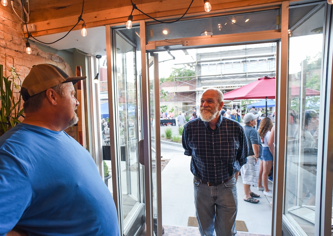 (Francisco Kjolseth  |  The Salt Lake Tribune)  Clay Iorg, left, owner of The Balance Rock Eatery & Pub, who has been renovating the eatery across the street along historic Main Street in Helper, Utah, visits with his neighbors, including artist David Richey Johnsen, center, during a recent gallery stroll known as Helper First Fridays. The monthly event is entering its second year, drawing visitors during a warm summer evening on Friday, Aug. 2, 2019.