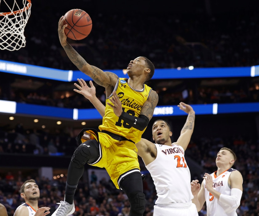 UMBC's Jairus Lyles (10) drives past Virginia's Isaiah Wilkins (21) and Kyle Guy (5) during the second half of a first-round game in the NCAA men's college basketball tournament in Charlotte, N.C., Friday, March 16, 2018. (AP Photo/Gerry Broome)