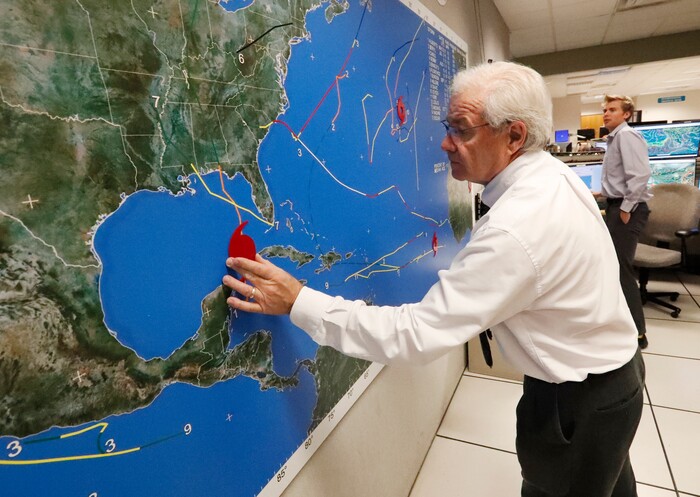 (Wilfredo Lee | The Associated Press) National Oceanic and Atmospheric Administration public affairs officer Dennis Feltgen updates the progress of Hurricane Michael on a large map, Tuesday, Oct. 9, 2018, at the Hurricane Center in Miami. At least 120,000 people along the Florida Panhandle were ordered to clear out Tuesday as Hurricane Michael rapidly picked up steam in the Gulf of Mexico and closed in with winds of 110 mph (175 kph) and a potential storm surge of 12 feet (3.7 meters).