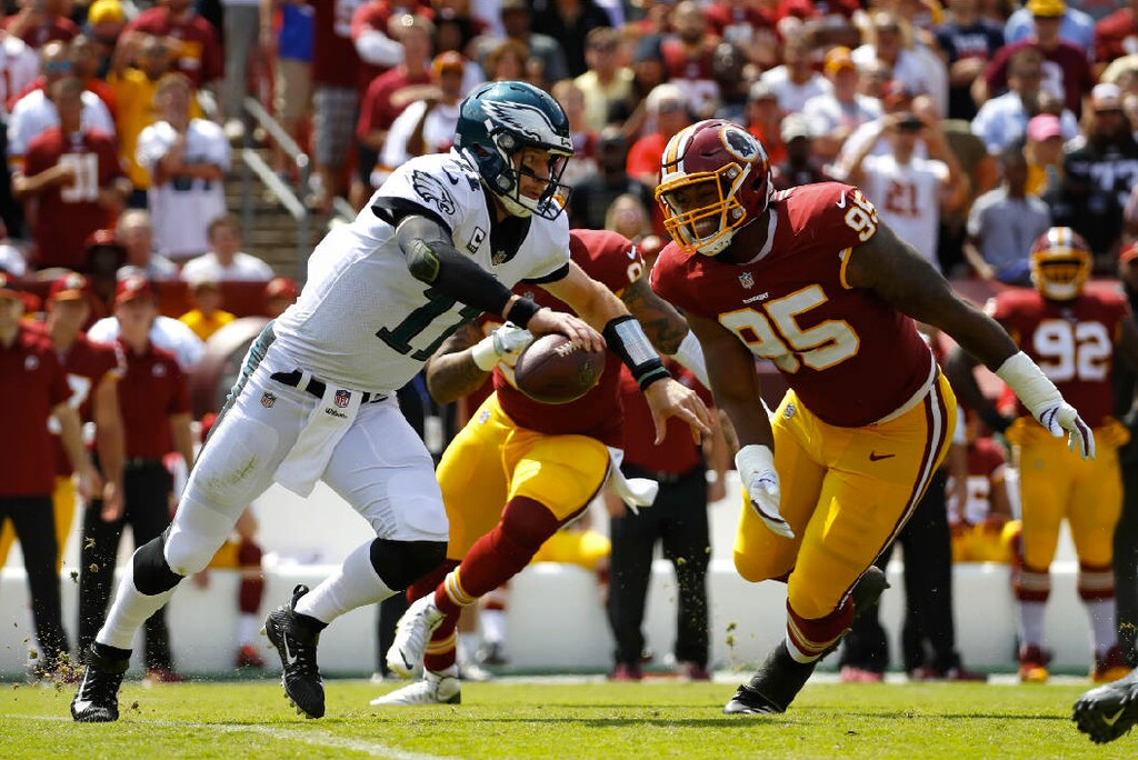 Philadelphia Eagles quarterback Carson Wentz, left, tries to outrun Washington defensive end Jonathan Allen (95) and outside linebacker Preston Smith as he looks for a receiver in the first half of an NFL football game, Sunday, Sept. 10, 2017, in Landover, Md. AP Photo| Alex Brandon.