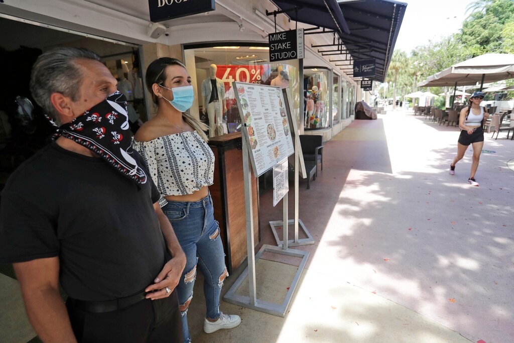 (Wilfredo Lee | AP) Restaurant workers Alvyn Lopez, left, and Maria Lindo watch for customers as they stand outside Aura at Books & Books, Monday, July 6, 2020, on Miami Beach, Florida's famed Lincoln Road. In Miami-Dade County, population 2.7 million, Mayor Carlos Gimenez ordered the closing of restaurants and certain other indoor places, including vacation rentals, seven weeks after they were allowed to reopen. Beaches will reopen on Tuesday after being closed over the weekend.