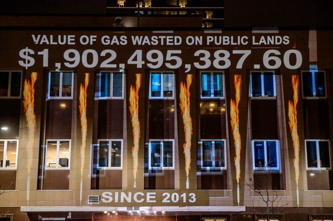(Trent Nelson | The Salt Lake Tribune)  In a visual protest, Alliance for Better Utah projects the total dollar value of natural gas lost on public lands since 2013 due to venting, flaring, and leaking onto the side of Federal Reserve Building in Salt Lake City, Thursday April 5, 2018.