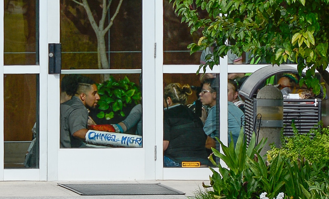 (Francisco Kjolseth  |  The Salt Lake Tribune)  Activists stage a protest against a private prison company with contracts to hold undocumented immigrants on Thursday, July 12, 2018, after locking themselves in the lobby at the headquarters of Management and Training Corporation in Centerville.