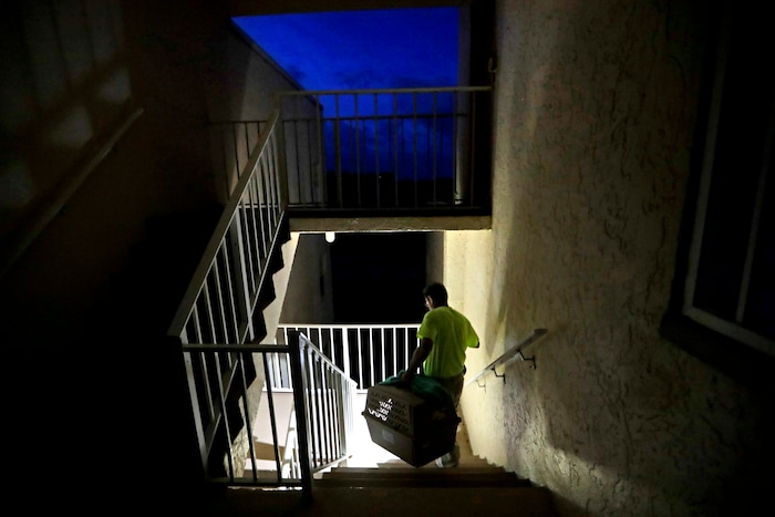 Joe Raymond carries a dog crate while leaving his mother's fourth floor apartment where he rode out Hurricane Irma with his family to return to their low lying home a mile away in Marco Island, Fla., Monday, Sept. 11, 2017. (AP Photo/David Goldman)