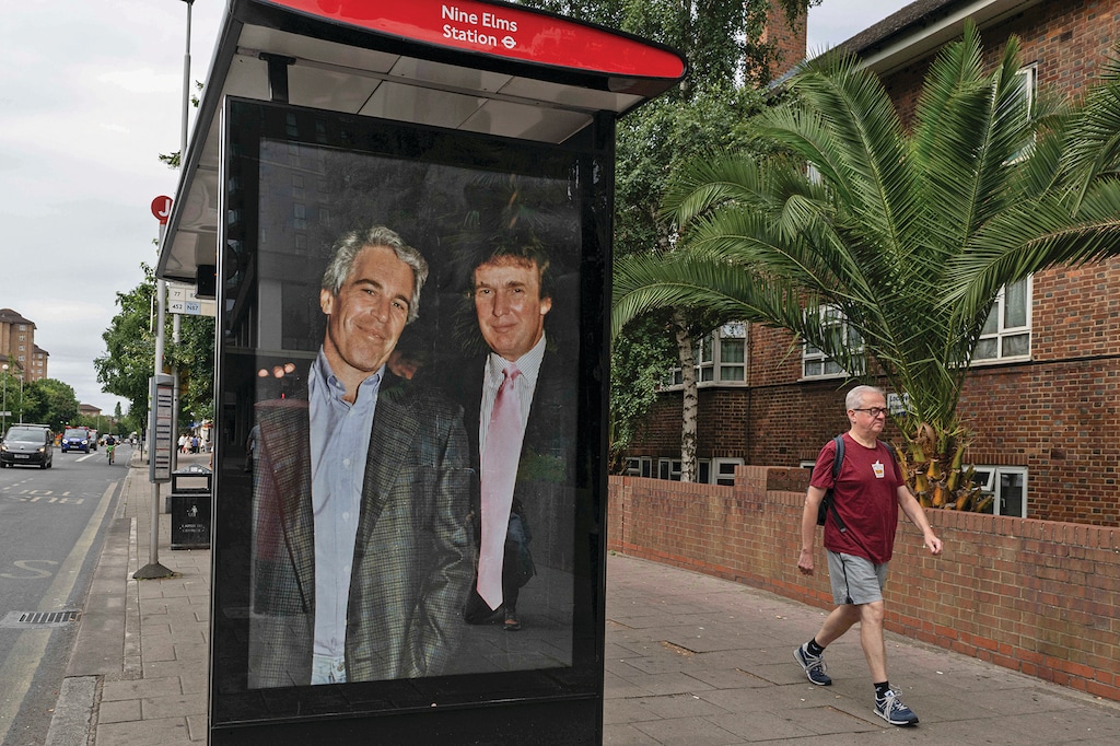 Commuters walk past a bus stop near Nine Elms Station as activists put up a poster showing President Donald Trump and Jeffrey Epstein near the US Embassy in London, Thursday, July 17, 2025.(AP Photo/Thomas Krych)