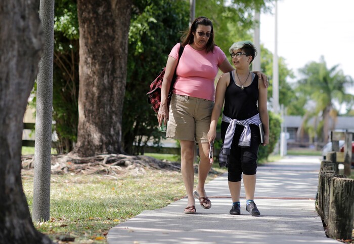 (Lynne Sladky | The Associated Press) In this Thursday, April 28, 2016 photo, Theo Ramos, 14, right, walks with his mother Lori, at a neighborhood park in Homestead, Fla. Ever since Lori learned of Theo’s gender dysphoria, she’d been in favor of her child identifying with whatever gender made him most comfortable. But taking potentially irreversible and powerful hormones was another matter entirely _ she said she wanted to postpone that as long as possible.
