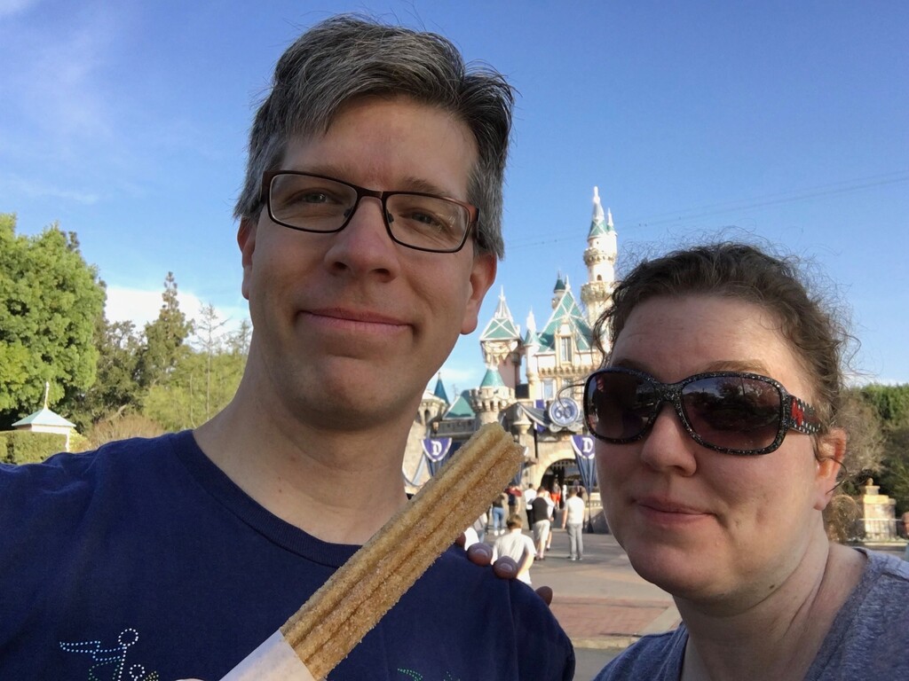 (Photo courtesy Tony Slade) Newly minted Disney "Mom" Tony Slade — holding a Disneyland churro — and his wife, Rae, in front of Sleeping Beauty's Castle.